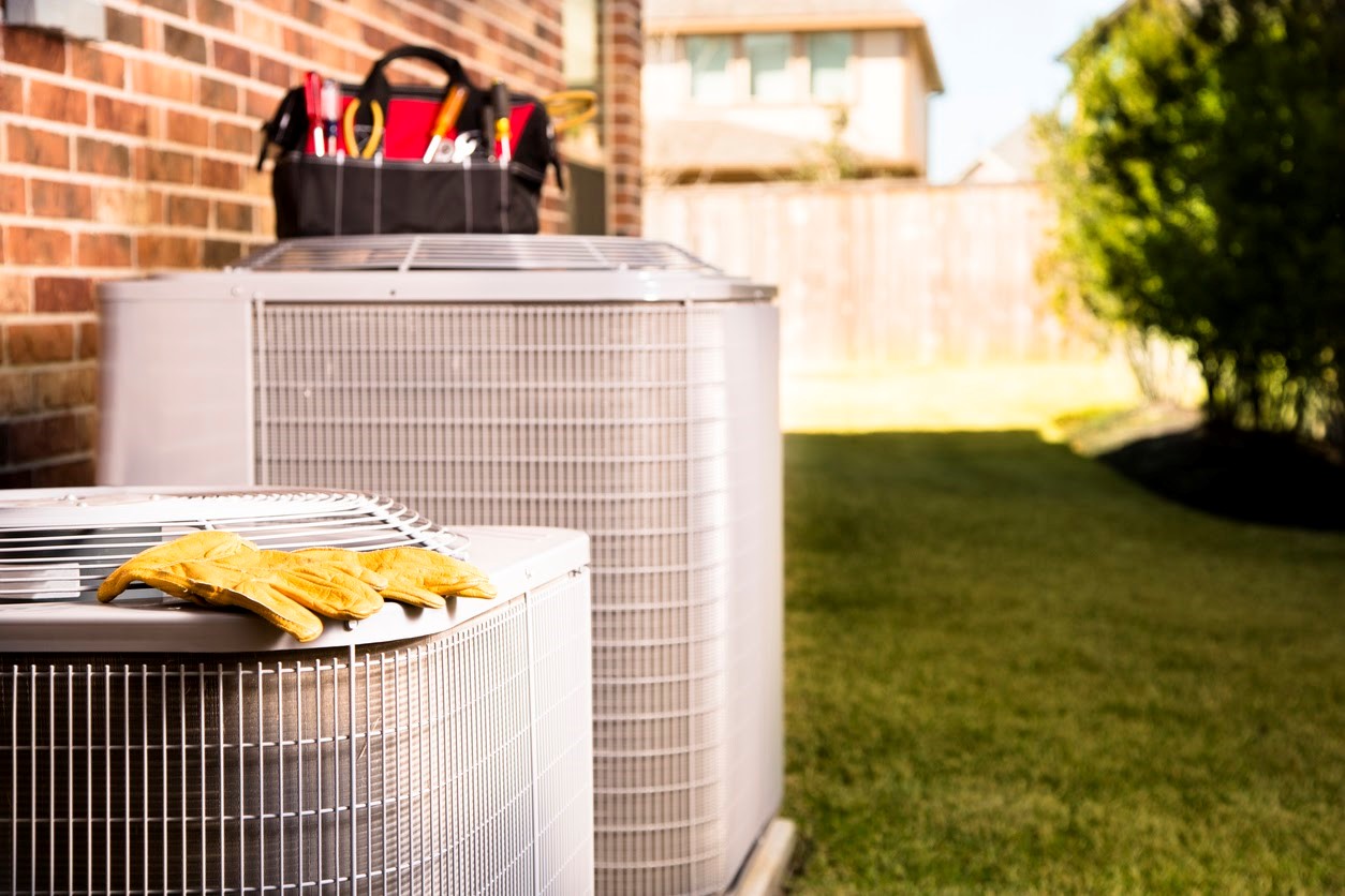 Two AC units outside a Northern Virginia home with CroppMetcalfe technician's tools and gloves. 
