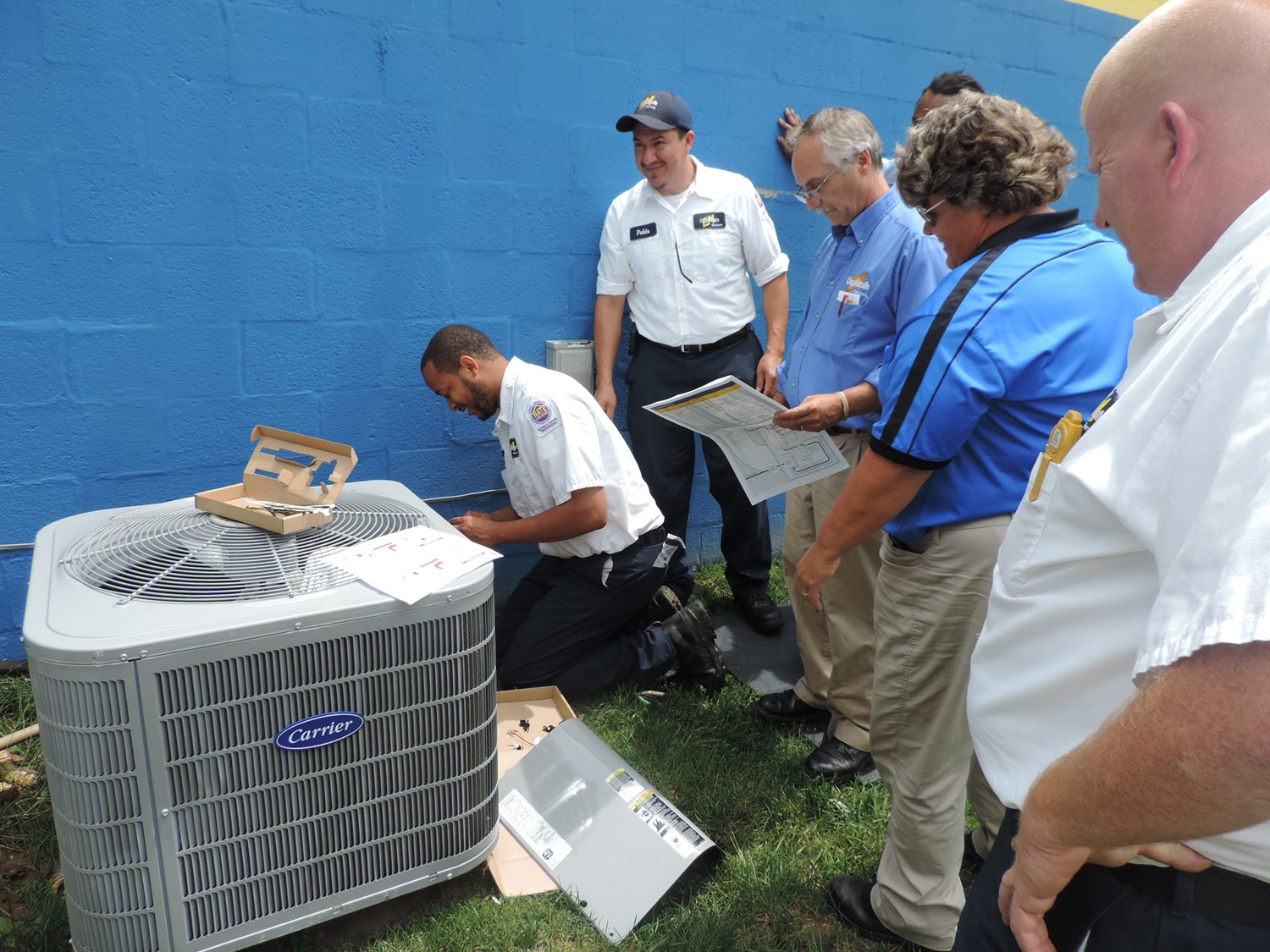 Multiple CroppMetcalfe technicians standing around an AC unit working on repairs. 