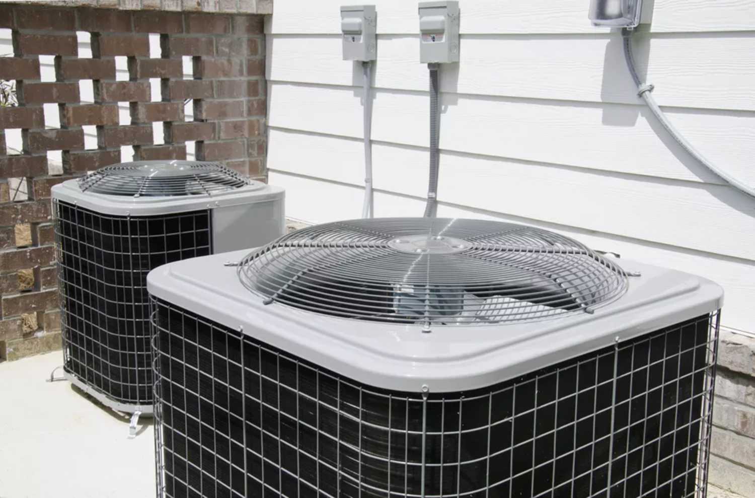 Two large grey air conditioning units outside a home in the D.C. region. 