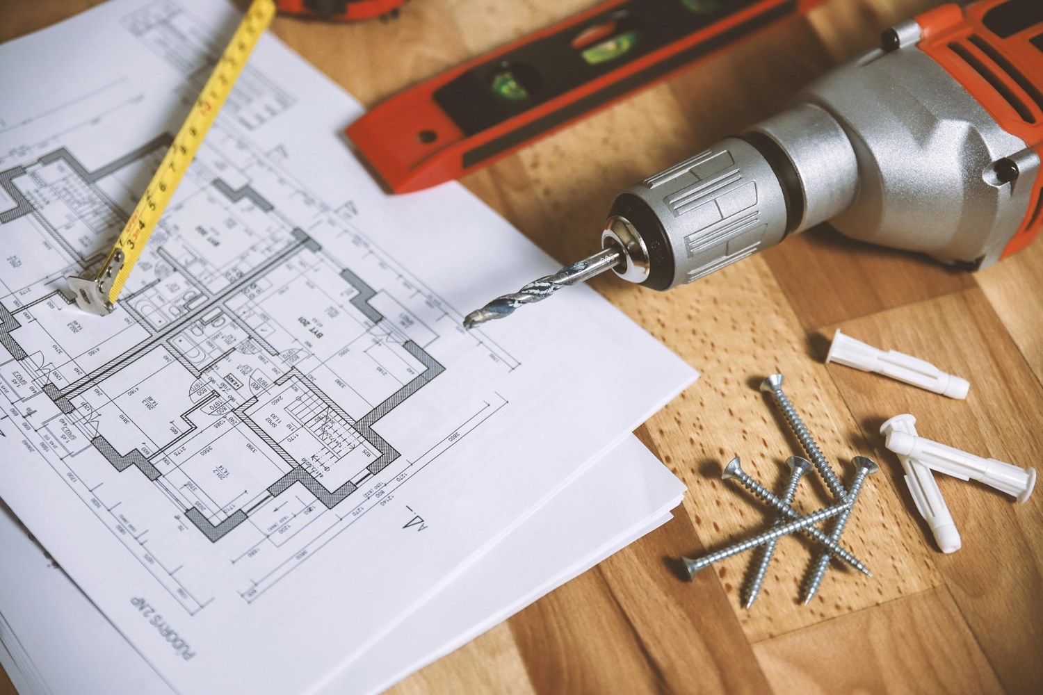 The layout of a single family home on a wooden table with construction tools surrounding it. 