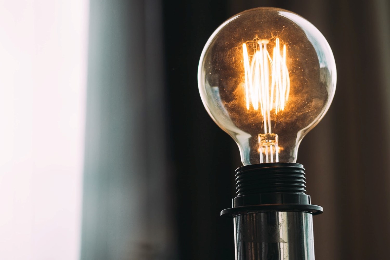 A close up of a light bulb that is plugged into an electrical outlet and turned on. 