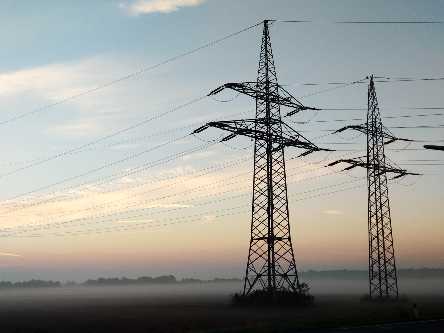 Two large electrical power lines with wires extending from the base based in a field.