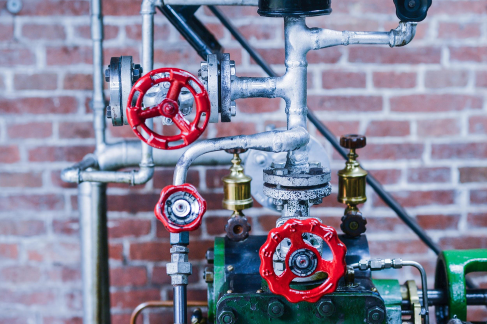 The plumbing system of a suburban home with numerous red gate vales and metal pipes. 