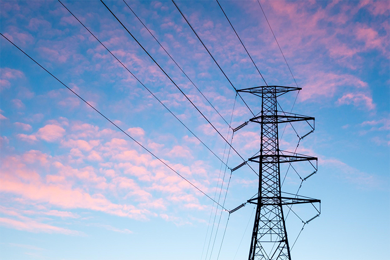 Large electrical power line with wires extending from the base standing in a field. 