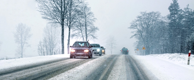 Multiple cars on a two lane street driving on snowy and icy roads in Northern Virginia. 