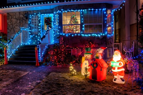 suburban home in the winter covered with Christmas lights and Christmas decorations in the yard.