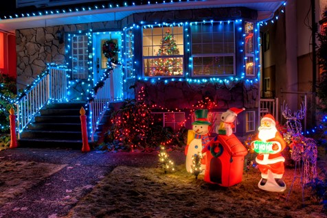 suburban home in the winter covered with Christmas lights and Christmas decorations in the yard. 